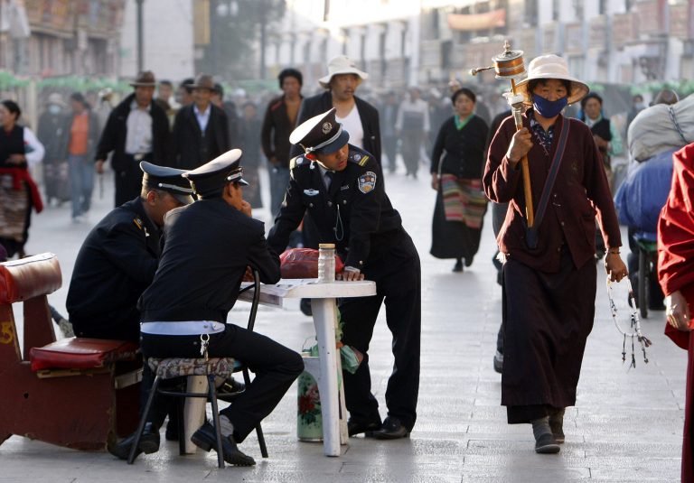   FILE - In this June 19, 2009 file photo, security guards keep watch over Buddhist pilgrims as they walk on the Barkhor, the circular route around the Jokhang Temple in Lhasa, the capital of Tibet, China. Tibet is seeing a boom in Chinese visitors, meaning that the government's latest ban on foreigners following self-immolation protests against Beijing's rule has barely dented the region's tourism industry. (AP Photo/Greg Baker, File)  