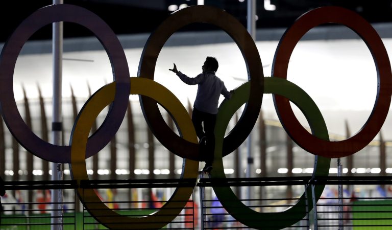 A man climbs on the Olympic rings near the basketball venue in the Olympic park on th eve before the opening ceremony of the 2016 Summer Olympics in Rio de Janeiro, Brazil, Thursday, Aug. 4, 2016. (AP Photo/Eric Gay)