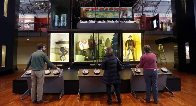  In this photo taken Wednesday, Dec. 26, 2012, museum employees interact with a wall of icons, including an Ivar's clam and Rainier beer reindeer from television commercials, and a model of the ferry Kalaka, at Seattle's Museum of History and Industry, in the city's South Lake Union neighborhood.