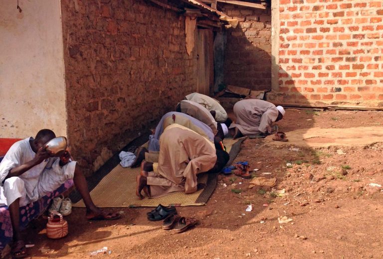 In this photo taken on Wednesday, March 5, 2014, Muslims pray outside a building in the  besieged town of Boda, Central African Republic. There is only one neighborhood in Boda where Muslims are safe from the bullets and machetes of Christian militia fighters. Those who venture out have been killed, their throats slit or their cars showered in gunfire. The town is home to one of the largest Muslim communities left in Central African Republic, though their plight is mirrored throughout the country. The about 4,000 Muslims who remain here are suffering in isolation and say they just want to leave for good after months of being targeted by the militiamen. (AP Photo/Krista Larson)