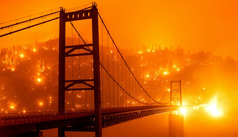 In this image taken with a slow shutter speed, embers light up a hillside behind the Bidwell Bar Bridge as the Bear Fire burns in Oroville, Calif., on Wednesday, Sept. 9, 2020.