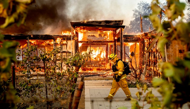 Woodbridge firefighter Joe Zurilgen passes a burning home as the Kincade Fire rages in Healdsburg, Calif., on Sunday, Oct 27, 2019.