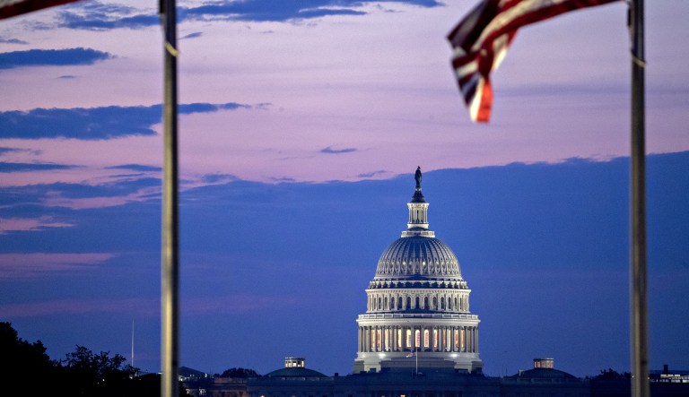 The U.S. Capitol building stands past American flags before sunrise in Washington, D.C., U.S., on Tuesday, July 11, 2017.