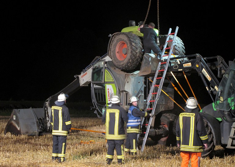 In this picture taken late Tuesday, July 29, 2014, firefighters try to set up a mechanical digger on a field near Isselburg, western Germany. German authorities say a man was killed and several others were injured when the digger tipped over and hit them during a so-called Cod Water Challenge, a dare that has been spreading on Facebook. (AP Photo/dpa, Guido Schulmann)