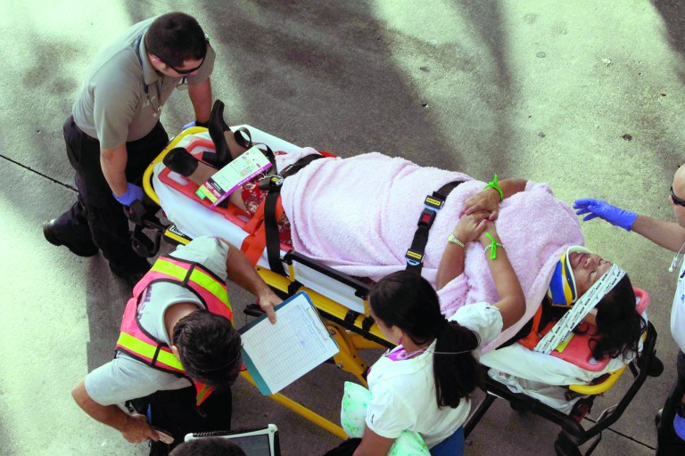 Emergency personnel attend to injured passengers after a bus accident at Miami International Airport on Saturday, Dec. 1, 2012 in Miami. Officials say a bus has hit an overpass, killing at least one person and injuring more than two-dozen people on board. Airport spokesman Greg Chin says the large, white bus hit the overpass going into the airport's arrivals section on Saturday morning. The bus was going about 20 mph when it clipped the roof entrance. (AP Photo/El Nuevo Herald, Roberto Koltun)