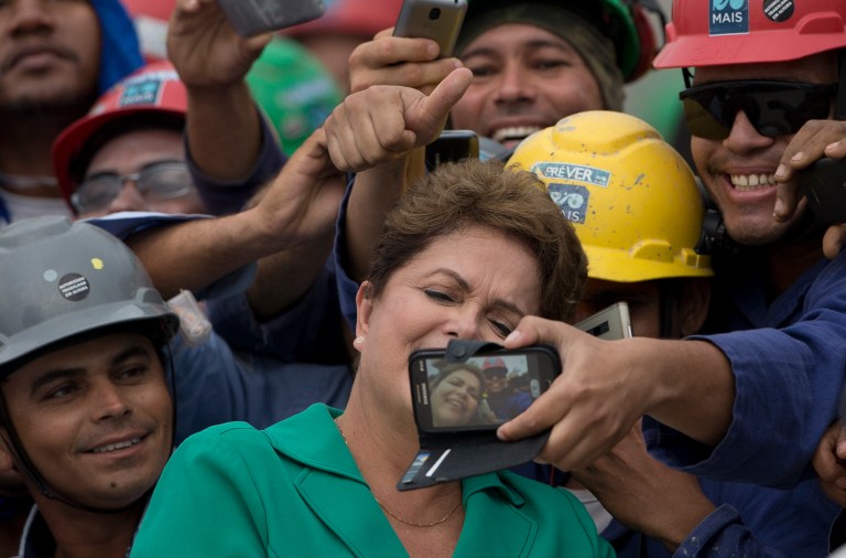 Brazil's President Dilma Rousseff, center, takes a selfie with workers during a visit to the Rio 2016 Olympic Park in Rio de Janeiro, Brazil, Tuesday, Sept.30, 2014. Chaired by Nawal El Moutawakel, the IOC Coordination Commission makes its seventh visit to Rio de Janeiro to monitor the preparation of the city for the 2016 Olympic and Paralympic Games. (AP Photo/Silvia Izquierdo)