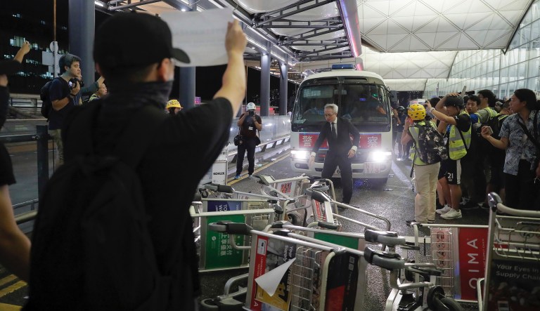 Protesters use luggage trolleys to block a police van during a demonstration at the Airport in Hong Kong, Tuesday, Aug. 13, 2019. Chaos has broken out at Hong Kong's airport as riot police moved into the terminal to confront protesters who shut down operations at the busy transport hub for two straight days. 