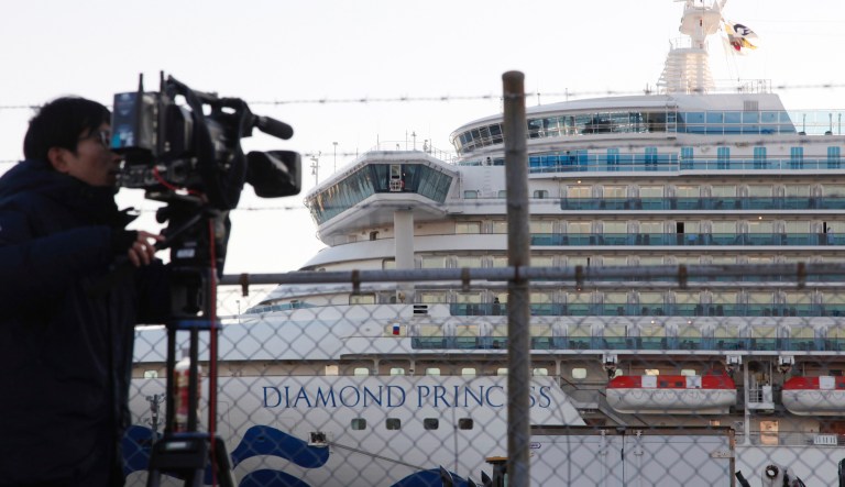 A TV cameraman films the quarantined ship Diamond Princess, background, anchored at Yokohama port in Yokohama, near Tokyo, Tuesday, Feb. 18, 2020. The cruise ship will begin letting passengers off the boat on Wednesday after itâs been in quarantined for 14 days.