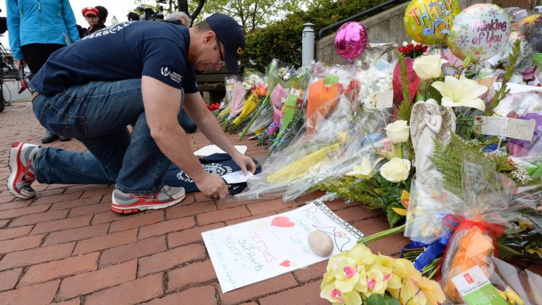 Jeff Pyke places a note outside Royal Canadian Mounted Police headquarters in Moncton, New Brunswick, on Friday, June 6, 2014. The suspect in the killing of three Royal Canadian Mounted Police was arrested unarmed early Friday, ending a massive manhunt that paralyzed much of the eastern Canadian city. (AP Photo/The Canadian Press, Sean Kilpatrick)
