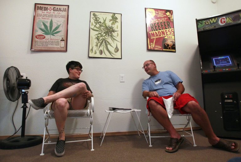 Co-owner Hollie Hillman talks with Longview, Wash., business owner Dave Grumbois as they wait inside her medical marijuana clinic for the first delivery of state-approved recreational marijuana so that she can begin sales across the parking lot at The Freedom Market in Kelso, Wash., on Tuesday, July 4, 2014. (AP Photo/The Olympian, Tony Overman)