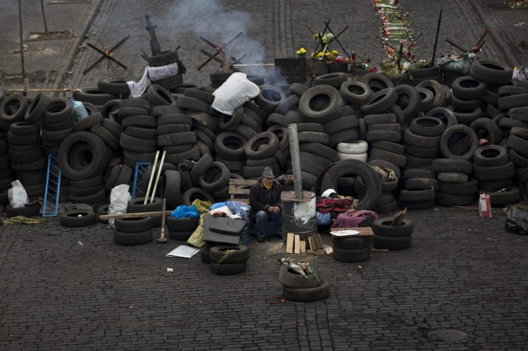 An anti-Yanukovych protester warms himself next to a fire as he guards a barricade in a street heading to Kiev's Independence Square, the epicenter of the country's current unrest, Ukraine, Friday, Feb. 28, 2014. Fugitive Ukrainian president Viktor Yanukovych on Friday pledged to fight for his country's future, in his first public appearance since disappearing from Ukraine. (AP Photo/Emilio Morenatti)