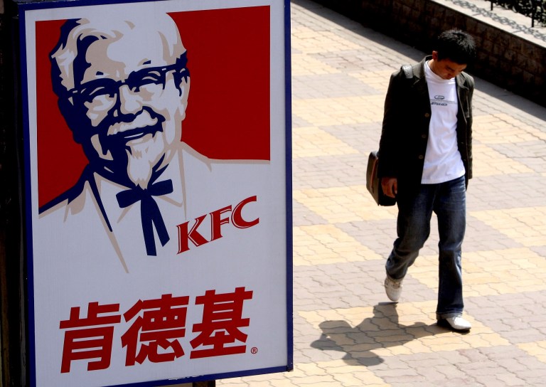   FILE - In this Thursday, March 29, 2007, file photo, a man walks past a sign for KFC in Shanghai, China. The owner of KFC and Pizza Hut said Thursday, Dec. 6, 2012, it is taking its fast-food menus to the lesser-known regions of China, with plans to set up shop in smaller cities throughout the key market. After expanding in China's biggest cities in recent years, Yum Brands Inc. is focusing on populating the country's less urbanized areas. (AP Photo/Eugene Hoshiko)  