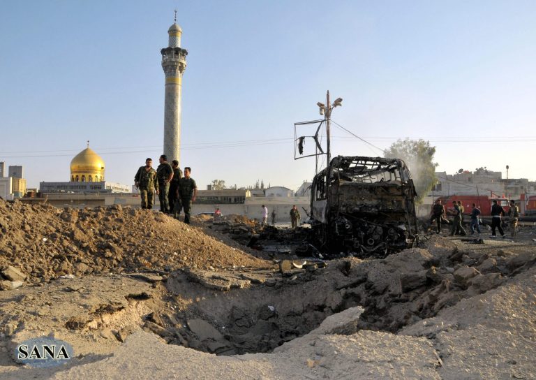   In this photo released by the Syrian official news agency SANA, Syrian soldiers stand at the explosion site where a car bomb exploded near the shrine of Sayyida Zeinab, seen in the background, suburb of Damascus, Syria, Thursday, June 14, 2012. A car bomb exploded Thursday in a Damascus suburb that is home to a popular Shiite Muslim shrine, wounding at least two people, Syria's state-run news agency SANA reported, while activists said regime troops continued shelling rebellious areas in central Homs province. (AP Photo/SANA)  