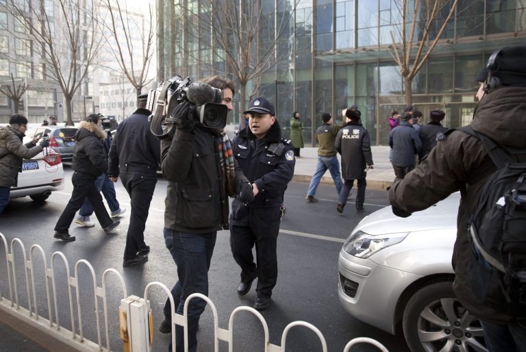 In this Sunday, Jan. 26, 2014 photo, policemen try to block journalists from interviewing Xu Zhiyong's lawyer Zhang Qingfang as he speaks to the media near the No. 1 Intermediate People's Court, in Beijing. The government is intensifying efforts to control foreign media coverage of China, blocking websites, harassing reporters trying to cover trials of activists in Beijing and thwarting efforts by The New York Times to station new journalists on the mainland. (AP Photo/Andy Wong)