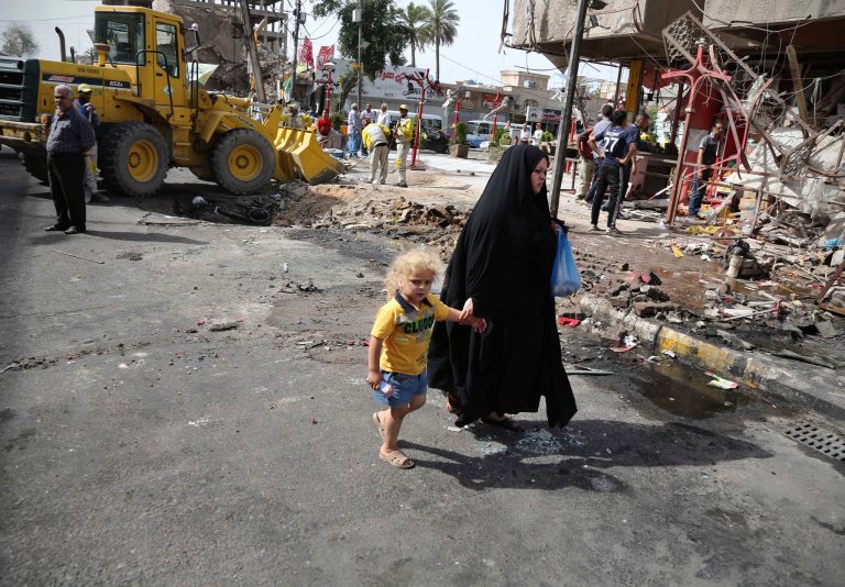 A woman walks with her child through the aftermath of a car bomb attack in the crowded commercial area of Karrada, in Baghdad, Iraq, Friday, April 18, 2014. Authorities in Iraq say a car bomb targeted a street full of shoppers in the capital. in Baghdad on Thursday,AP Photo/Karim Kadim)