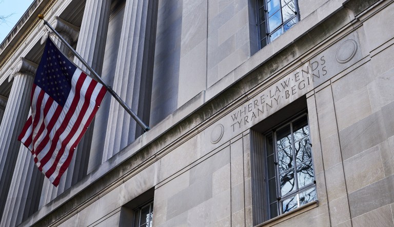An American flag flies outside the U.S. Department of Justice (DOJ) headquarters in Washington, D.C., U.S., on Friday, Feb. 2, 2018. Federal Bureau of Investigation and Justice Department officials got a warrant to spy on a Trump campaign associate by misleading a surveillance court judge, House Republicans contend in a newly released memo that Democrats have dismissed as a contrived account intended to protect the president.