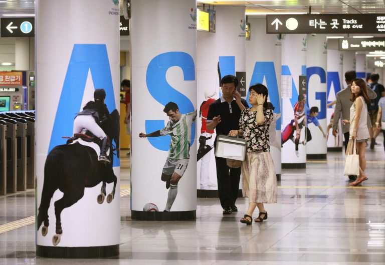 People pass by 2014 Asian Games posters at a subway station in Seoul, South Korea, Thursday, July 10, 2014. North Korea's Korean Central News Agency on Thursday said the North proposed a meeting at a border village next Tuesday to discuss its Asian Games participation.(AP Photo/Ahn Young-joon)
