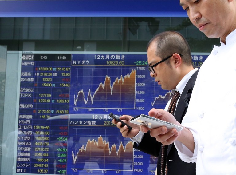 FILE - In this July 1, 2014 file photo, passers-by use cellphones in front of electronic stock board of a securities firm in Tokyo. The Treasury Department on Wednesday, July 16, 2014 reported that total foreign holdings rose 0.3 percent to $5.98 trillion, up from $5.96 trillion in April. (AP Photo/Koji Sasahara, File)