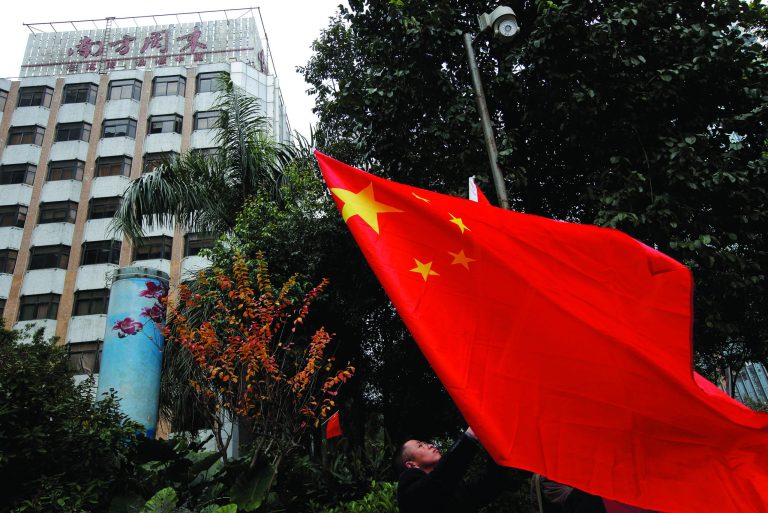 A leftist raises a Chinese national flag during a counter-protest against supporters of the Southern Weekly newspaper outside the headquarters of the newspaper in Guangzhou, Guangdong province, China Wednesday, Jan. 9, 2013. Communist Party-backed management and rebellious editors at the influential weekly newspaper have defused a high-profile standoff over censorship that turned into a test of the new Chinese leadership's tolerance for political reform. (AP Photo/Vincent Yu)