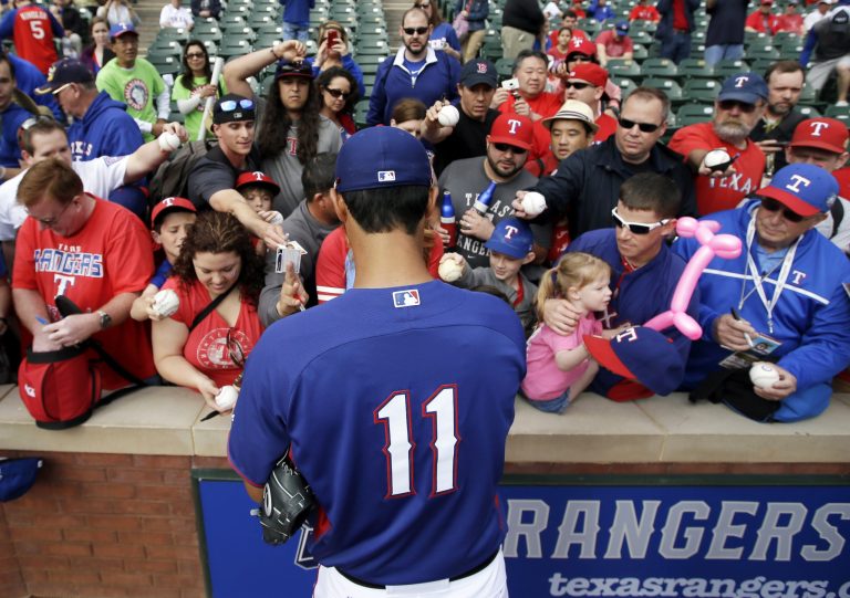 Texas Rangers' Yu Darvish, of Japan, signs autographs for fans before a baseball game against the Philadelphia Phillies, Monday, March 31, 2014, in Arlington, Texas. (AP Photo/Tony Gutierrez)
