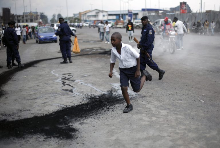   A Congolese schoolboy runs past police officers who extinguished a burning tyre set alight by demonstrators in Goma, eastern Congo, Thursday Dec. 6, 2012. Dozens of Congolese demonstrated in the provincial capital of Goma on Thursday against what they described as the impotence of the countryâs armed forces, which allowed a rebel group to overrun the city a little over two weeks ago. They also decried the passivity of United Nations peacekeepers, who did little to stop the fighters saying it was not within their mandate. (AP Photo/Jerome Delay)  