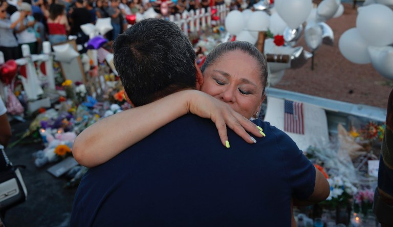 Mariana Cordero, right, embraces Gilbert Reza at a makeshift memorial at the scene of a mass shooting at a shopping complex, Tuesday, Aug. 6, 2019, in El Paso, Texas.