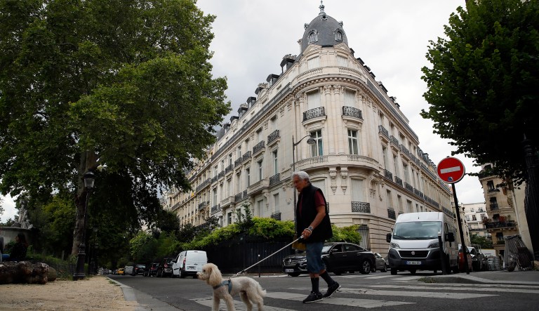 A man walks his dog next to an apartment building owned by Jeffrey Epstein in the 16th district in Paris, Tuesday, Aug. 13, 2019.