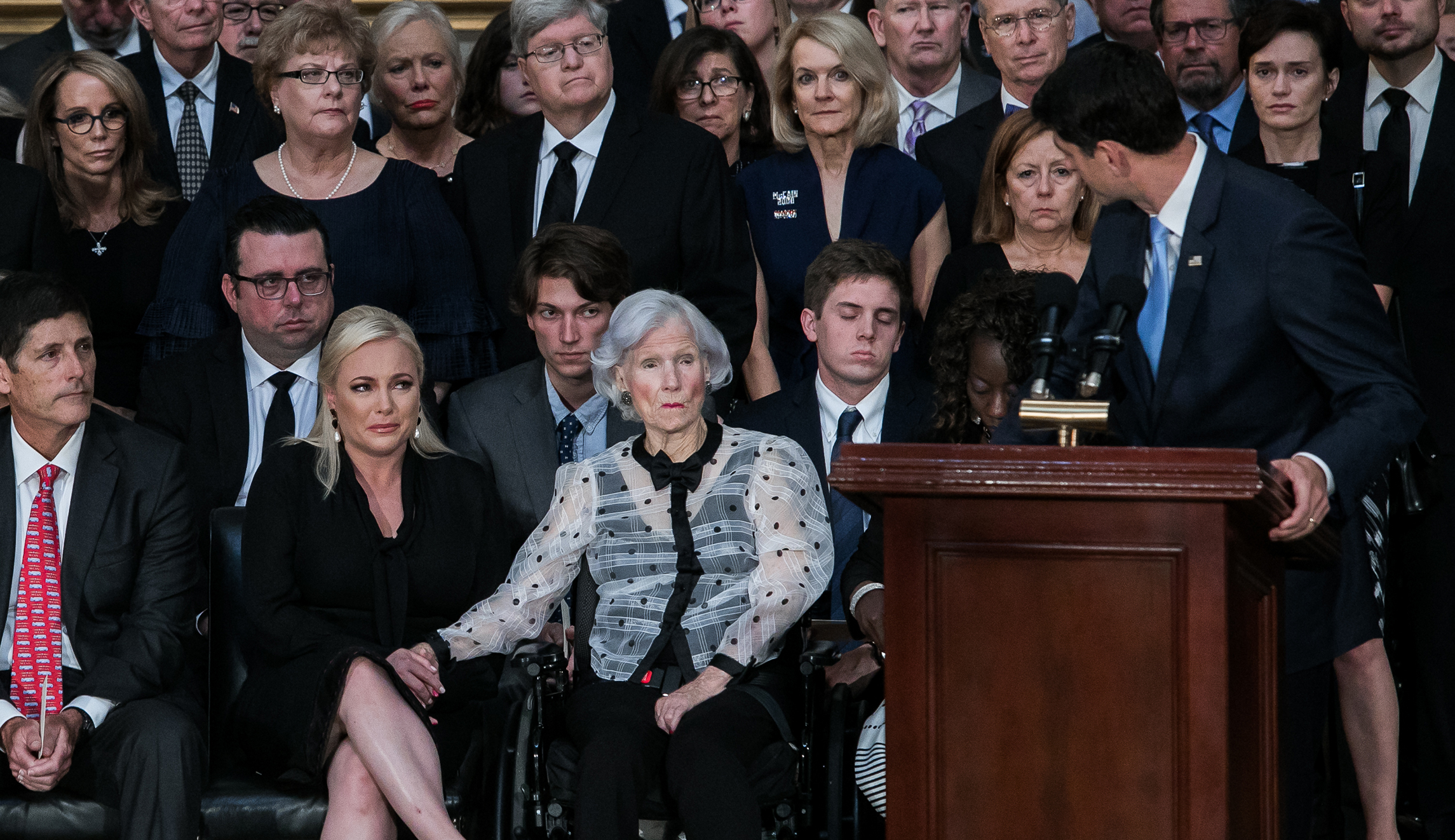 House Speaker Paul Ryan (right) gives a speech as Roberta McCain (pictured center), Meghan McCain (pictured second-left), and other members of Sen. John McCain's family look on.