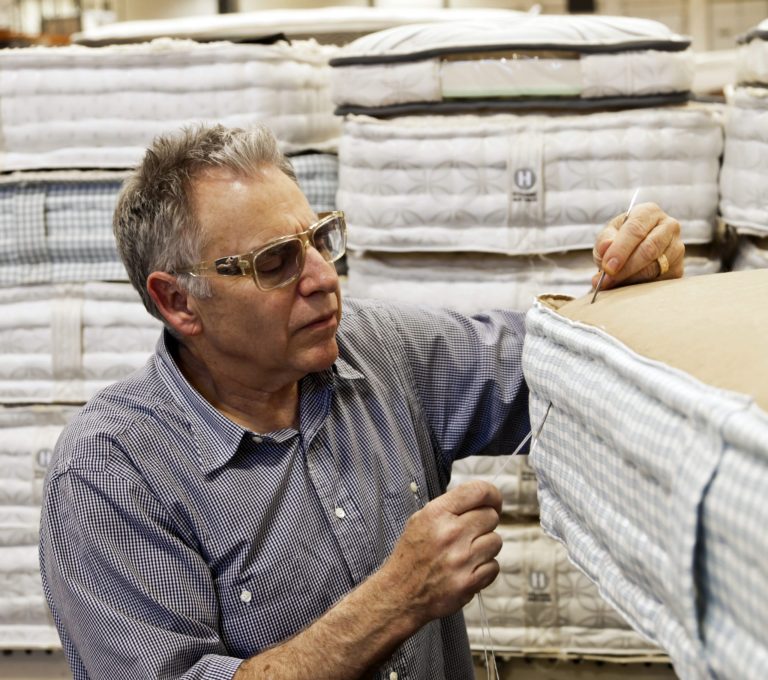   FILE- In this May 9, 2012 file photo, businessman Earl Kluft, who manufactures luxury mattresses, hand-stitches the side walls of an Aireloom handmade bed at his factory in Rancho Cucamonga, Calif. U.S. factories produced less in May than April, as automakers cut back on output for the first time in six months, according to the Federal Reserve, Friday, June 15, 2012. The report indicates that manufacturing, a key driver of the economic growth, is slowing. (AP Photo/Damian Dovarganes, File)  