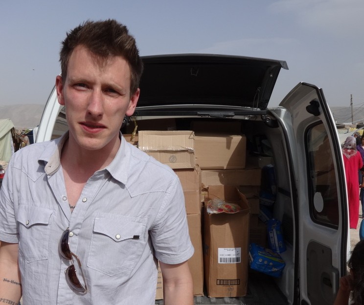 Peter Kassig standing in front of a truck filled with supplies for Syrian refugees. A new graphic video purportedly produced by Islamic State militants in Syria released Sunday Nov. 16, 2014 claims U.S. aid worker Kassig was beheaded. (AP Photo/Courtesy Kassig Family, File)