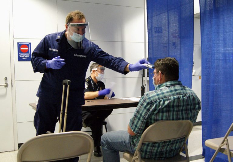 In this Thursday, Oct. 16, 2014, photo released by U.S. Customs and Border Protection, U.S. Coast Guard Health Technician Nathan Wallenmeyer, left, and CBP supervisor Sam Ko conduct prescreening measures on a passenger, right, who arrived from Sierra Leone at O'Hare International Airport's Terminal 5 in Chicago. (AP Photo/U.S. Customs and Border Protection, Melissa Maraj)