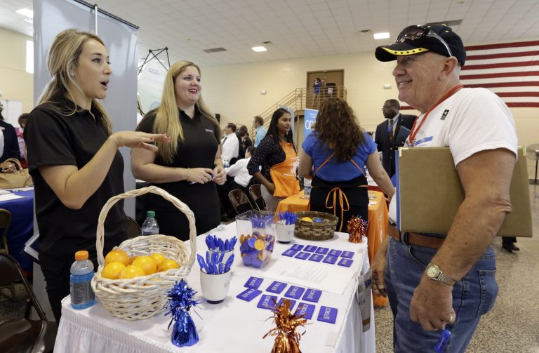 In this photo taken Wednesday, July 16, 2014, job seeker U.S. Army veteran John Godman, right, talks to recruiters Nicole Rushton, left, and Megan Hogan, center, at a Hiring Fair For Veterans in Fort Lauderdale, Fla. The Labor Department releases weekly jobless claims on Thursday, July 23, 2014. (AP Photo/Alan Diaz)