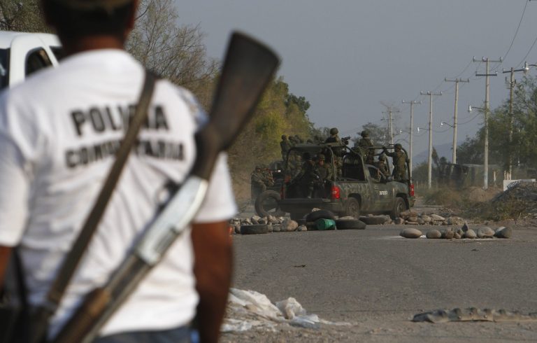 Local self-defense squads watch as Mexican army soldiers enter the town of La Ruana, Michoacan, Mexico, Monday, May 20, 2013. Residents of western Mexico towns who endured months besieged by a drug cartel are cheering the arrival of hundreds of Mexican army troops. Hundreds of people in the state of Michoacan have taken up arms to defend their villages against drug gangs, a vigilante movement born of frustration at extortion, killings and kidnappings in a region wracked by violence. (AP Photo/Marco Ugarte)