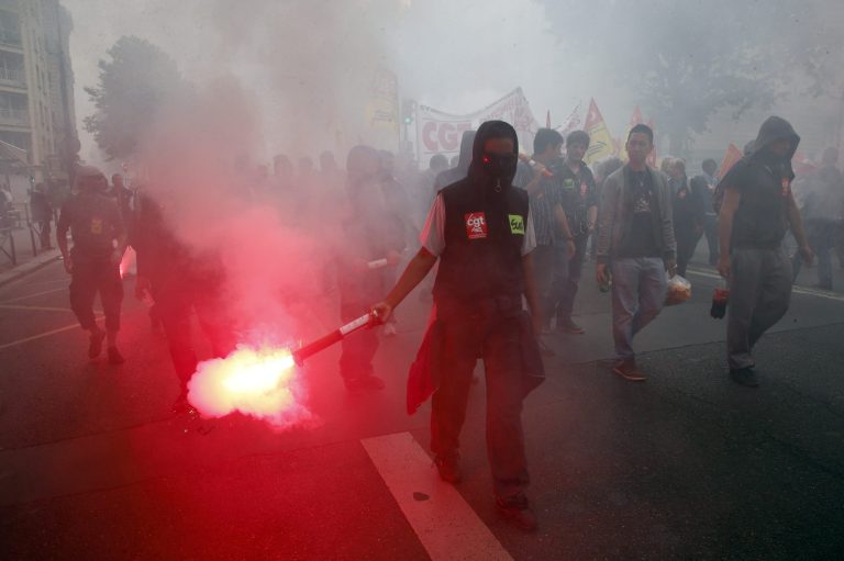 A demonstrator holds a flare during a demontration march of French national railway SNCF in Paris, Thursday, June 19, 2014.  They are striking over plans to streamline and open the state-run network, considered among the world's best, to private competition. A week into a nationwide train strike that has tangled traffic and stranded tourists and has caused some of the worst disruption to the country's rail network in years.(AP Photo/Francois Mori)