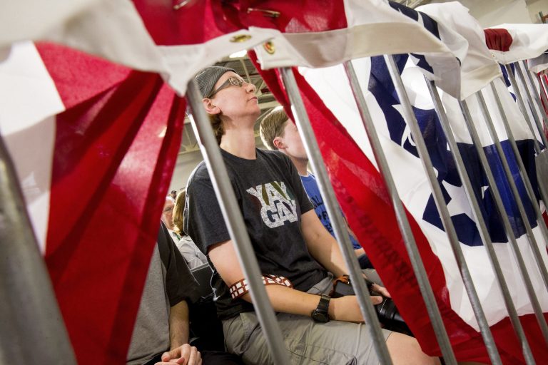 A member of the audience wears a shirt that reads 