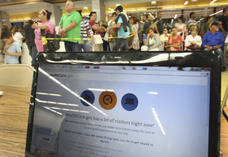 People wait in line to see an agent from Sunshine Life and Health Advisors as the Affordable Care Act website reads, 'HealthCare.gov has a lot of visitors right now!' at a store set up in the Mall of Americas in Miami, Fla. (Joe Raedle/Getty Images)