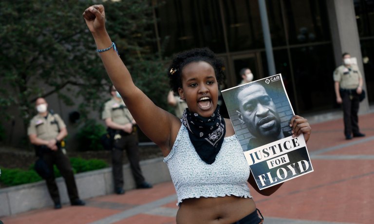 A protester holds a photo of George Floyd during a protest at the Hennepin County Government Center, Thursday, May 28, 2020, as protests continue over the death of George Floyd, who died in police custody Monday night in Minneapolis after video shared online by a bystander showed a white officer kneeling on his neck during his arrest as he pleaded that he couldn't breathe.