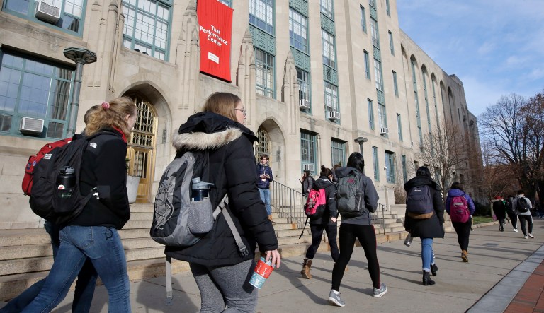 In this Nov. 29, 2018 photo students and passers-by carry book bags as they walk past an entrance to Boston University College of Arts and Sciences, in Boston.
