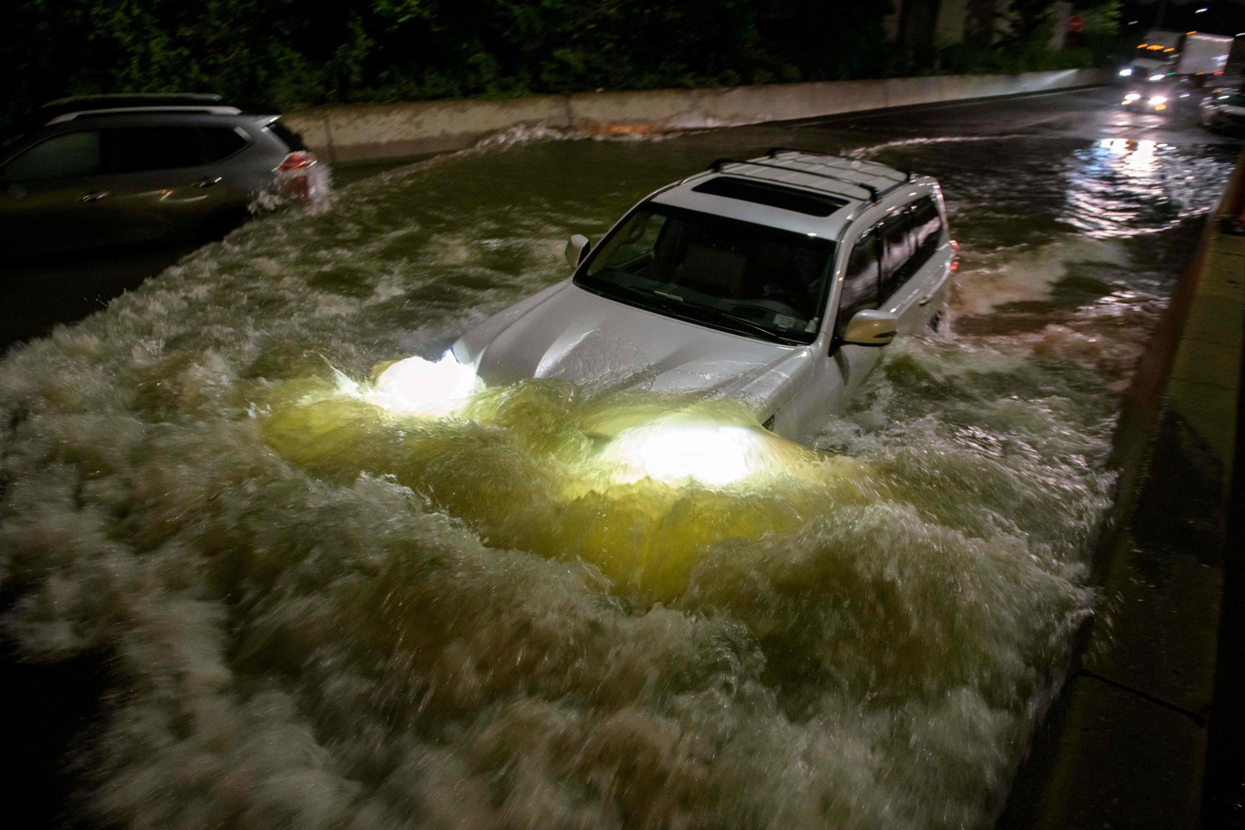 A motorist drives a car through a flooded expressway in Brooklyn