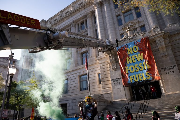 District of Columbia fire fighters remove an Extinction Rebellion demonstrator who scaled the John A. Wilson Building during a rally on Earth Day in Washington, D.C., U.S., on Friday, April 22, 2022.