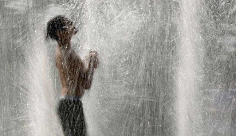 A boy plays in a fountain to cool off as temperatures approach 100 degrees Fahrenheit (38 Celsius) Thursday, July 18, 2019, in Kansas City, Mo.