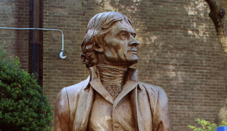 FILE - In this Sept. 23, 2016 file photo taken at the Thomas Jefferson statue on the Hofstra University campus in Hempstead, N.Y., students assisting with an upcoming presidential debate pose with the statue, which some students at the school would now liked removed because Jefferson was a slave owner who believed black people were inherently inferior to whites. From left are Madison Wright, Jordan Heiden, and Qian Xiong.