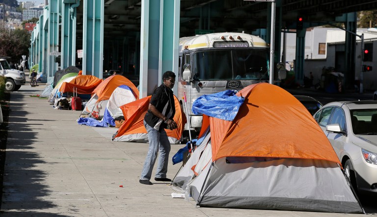 FILE - In this Feb. 23, 2016 file photo, a man stands outside his tent on Division Street in San Francisco. San Francisco voters will decide in November 2018 whether to tax large businesses to pay for homeless and housing services in a city struggling with income inequality. Supporters collected enough signatures to get the measure on the ballot.