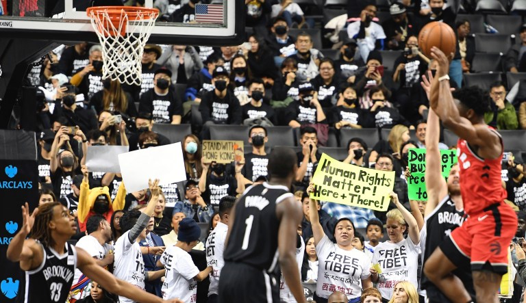 Activists raise signs referencing the NBA's recent controversy during the fourth quarter of a preseason NBA basketball game between the Toronto Raptors and the Brooklyn Nets Friday, Oct. 18, 2019, in New York.