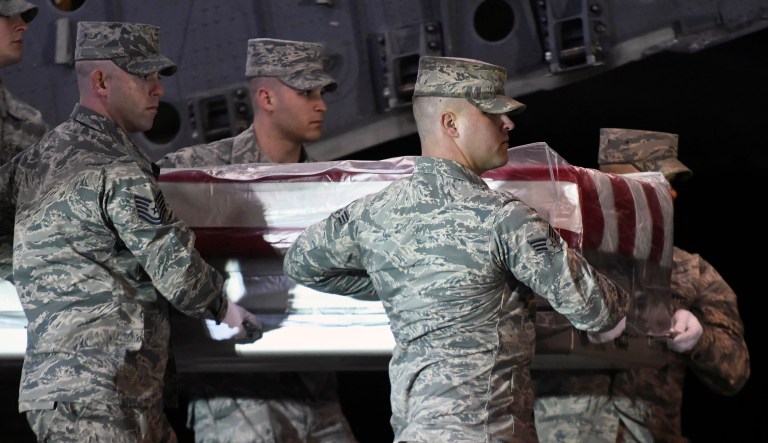 An Iraqi soldier stands guard in front of smoke rising from a fire set by pro-Iranian militiamen and their supporters in the U.S. embassy compound, Baghdad, Iraq, Wednesday, Jan. 1, 2020. 