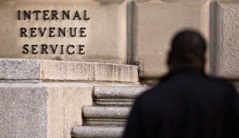 A man walks past the Internal Revenue Service (IRS) headquarters in Washington, D.C., U.S., on Friday, Oct. 20, 2017. President Donald Trump's top legislative priority took a major step forward as the Senate narrowly approved a budget vehicle for tax cuts -- but sharp divides over an array of non-binding amendments revealed the towering challenge he faces from here.