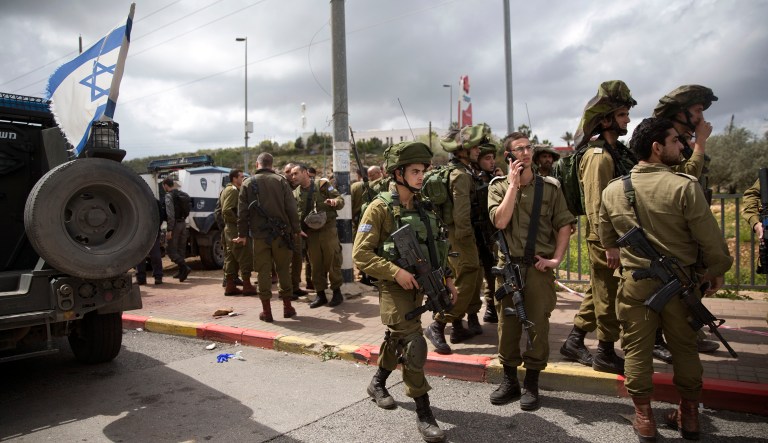 Israeli soldiers stand guard at the scene of an attack in the West Bank Jewish settlement of Ariel, Thursday, March 17, 2016. Israeli security forces on Thursday shot and killed two Palestinians who stabbed and wounded a 20-year-old woman shortly after she got off a bus at the West Bank Jewish settlement of Ariel, an Israel Defense Forces spokesperson said.
