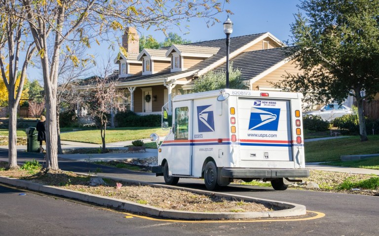 A USPS truck sits outside a house.