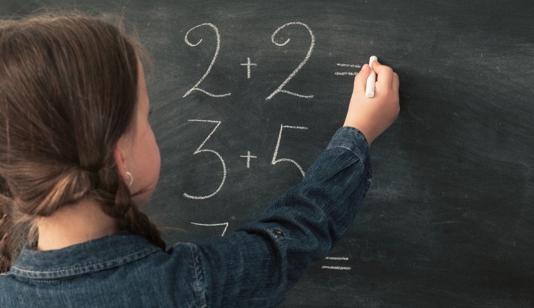 Young girl doing math on a chalkboard.