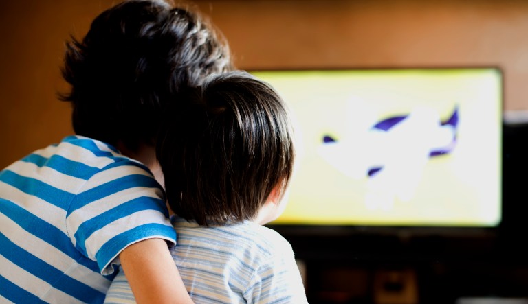 Two children sit and watch TV.